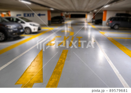Yellow markings with blurred modern cars parked inside closed underground parking lot. Yellow markings with blurred modern cars parked inside closed underground parking lot. 89579681