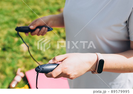Close up of woman jumping, girl using skipping rope in park, summer sunny day Close up of woman jumping, girl using skipping rope in park, summer sunny day 89579995