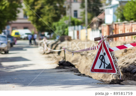 Construction roadwork on street in city. Red safety sign warns about roadworks. Be careful, danger on your way Construction roadwork on street in city. Red safety sign warns about roadworks. Be careful, danger on your way 89581759