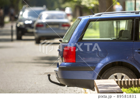 Blue car parked on sunny street, red stop lights, hook for dragging trailer, tow hitch or towbar. 89581831