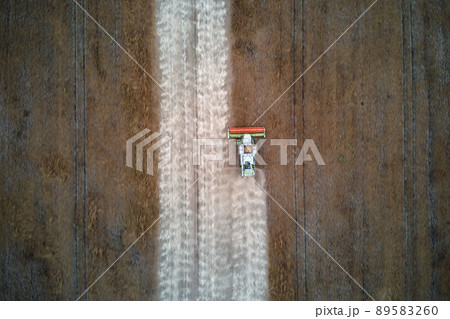 Aerial view of combine harvester working during harvesting season on large ripe wheat field. Agriculture concept 89583260