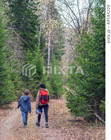 Mom and son are going hiking on a forest road uphill. Mom and son are going hiking on a forest road uphill. 89584209