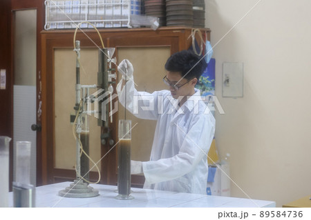 Asian man scientist make sediment experiment with old equipment and measuring cylinder in the laboratory 89584736