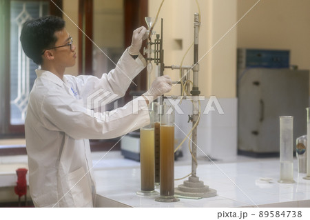 Asian man scientist make sediment experiment with old equipment and measuring cylinder in the laboratory Asian man scientist make sediment experiment with old equipment and measuring cylinder in the laboratory 89584738