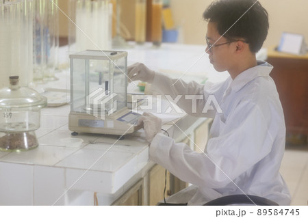 Asian man scientist operating digital laboratory scale in the laboratory Asian man scientist operating digital laboratory scale in the laboratory 89584745