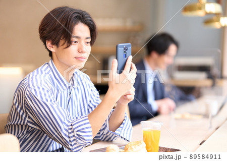 カフェでスマホの画面を見つめる若い男性 89584911