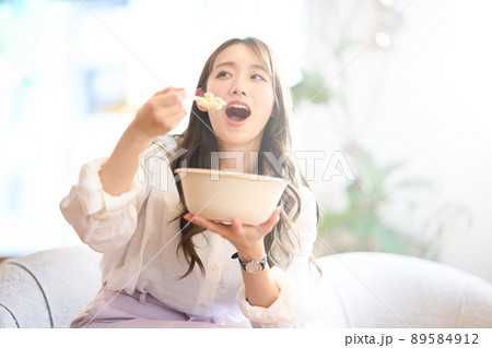 サラダボウルを手にして野菜を食べる若い女性 サラダボウルを手にして野菜を食べる若い女性 89584912