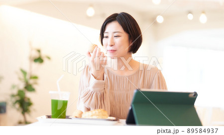 食事をとりながらPCを使う笑顔の若い女性 89584937