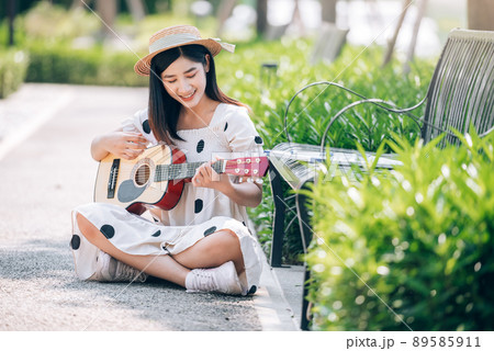 Asian woman playing guitar in the park, lifestyle and recreation concept. 89585911