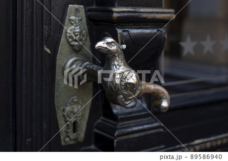 Old door handle. Wooden vintage entrance door with antique door handles in the shape of bird. Selective focus 89586940