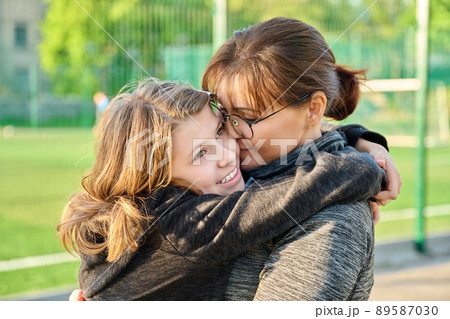 Portrait of happy mom and preteen daughter hugging together outdoor 89587030