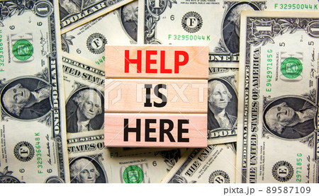 Help is here and support symbol. Concept words Help is here on wooden blocks on beautiful background from dollar bills. Business, support, help is here concept. Copy space. 89587109