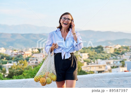 Outdoor portrait of beautiful mature woman with smartphone, summer nature sky 89587397