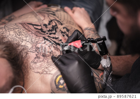 Master of the art of tattooing working on professional tattoo machine gun in the salon 89587621