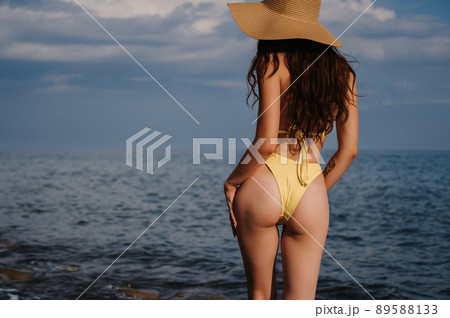 sexy ass of a slender girl in a swimsuit in a straw hat on the beach at the sea sexy ass of a slender girl in a swimsuit in a straw hat on the beach at the sea 89588133