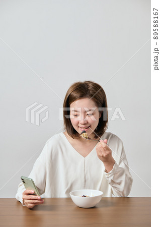 スマホを見ながらオートミールを食べる若いヴィーガン女性 89588167
