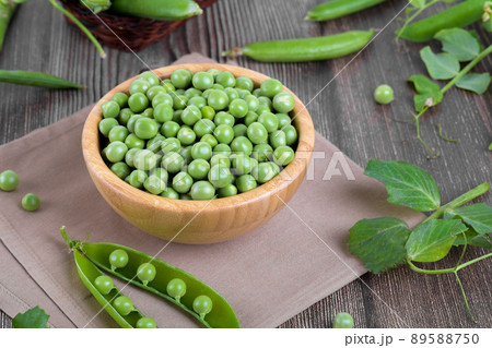 Fresh organic raw green peas in a bowl with peas plants leaves on dark wooden table background, bean protein, close up 89588750