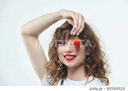 attractive girl with a smile holds a strawberry berry in her hands. 89589029