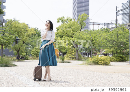 一人旅の女性がスーツケースを持って考え事をしている 89592961