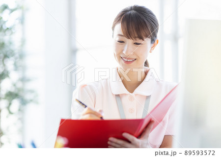 施設内でファイルと筆記用具を持つ医療従事者の女性 89593572