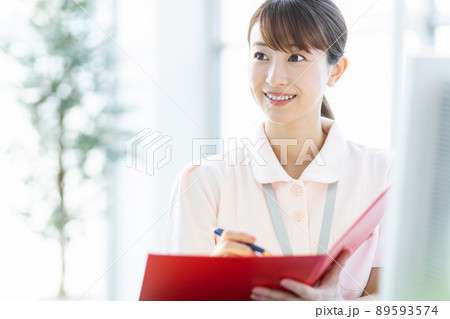 施設内でファイルと筆記用具を持つ医療従事者の女性 89593574