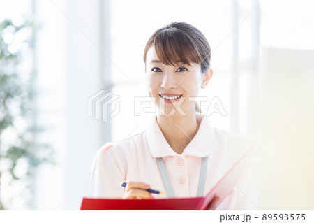 施設内でファイルと筆記用具を持つ医療従事者の女性 施設内でファイルと筆記用具を持つ医療従事者の女性 89593575