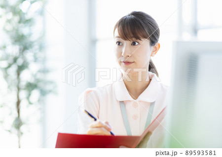 施設内でファイルと筆記用具を持つ医療従事者の女性 施設内でファイルと筆記用具を持つ医療従事者の女性 89593581