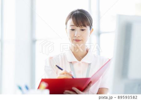 施設内でファイルと筆記用具を持つ医療従事者の女性 施設内でファイルと筆記用具を持つ医療従事者の女性 89593582