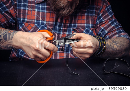Man working with leather cutting leather outlines for his new production in his studio 89599080