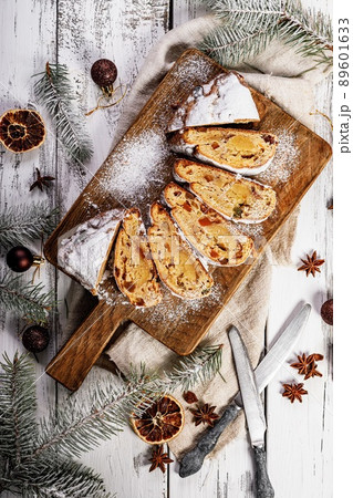 Christmas stollen on a cutting board. Wooden white table background. Traditional Christmas pastry with marzipan, nuts, raisins and dried fruit. Top view 89601633
