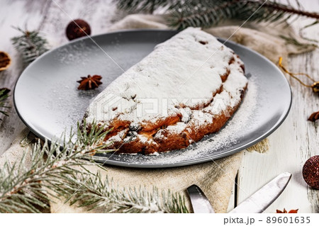 Christmas stollen on a gray plate. Wooden white table background. Traditional Christmas pastry with marzipan, nuts and raisins. Copy space Christmas stollen on a gray plate. Wooden white table background. Traditional Christmas pastry with marzipan, nuts and raisins. Copy space 89601635