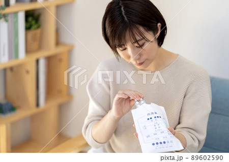 薬袋から飲み薬を取り出す女性 89602590