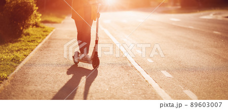 Woman riding on scooter on asphalt road in summer 89603007