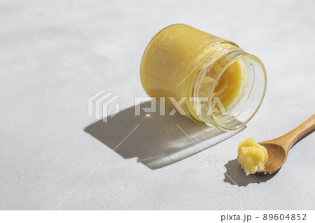 Ghee in a glass jar made with sunflower oil on a light background, copy space for text. Hard light. 89604852