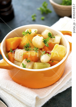 Close up baked root vegetables in orange bowl. Vegan food. Close up baked root vegetables in orange bowl. Vegan food. 89604857