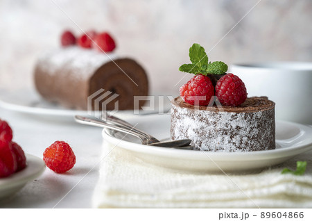 Slice of chocolate roll cake or swiss dessert cake with raspberries. 89604866