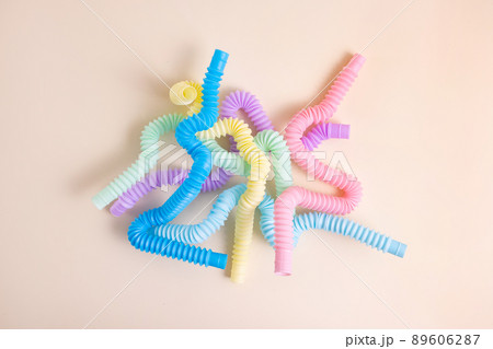 Trendy kids toys pastel colorful pop-tube on beige background. Set of forms and colors corrugated pipe and anti stressing, relaxation fidget finger toys. Trendy kids toys pastel colorful pop-tube on beige background. Set of forms and colors corrugated pipe and anti stressing, relaxation fidget finger toys. 89606287