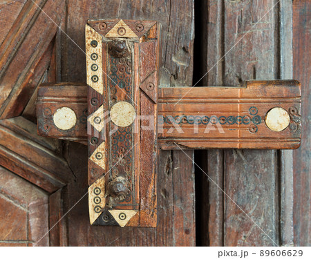Wooden aged ornate latch over a wooden door 89606629