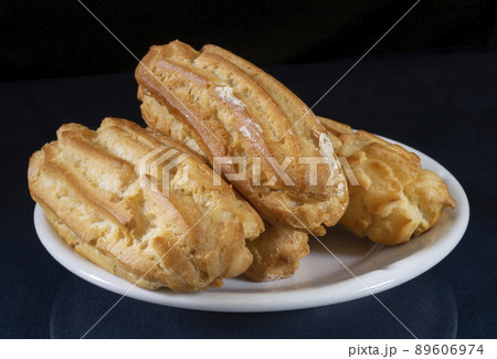 Sweet pastries in a white plate on a black background Sweet pastries in a white plate on a black background 89606974