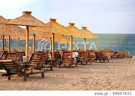 Straw umbrellas on tropical idyllic resort. Blue sea and sky with soft yellow sunlight. Straw umbrellas on tropical idyllic resort. Blue sea and sky with soft yellow sunlight. 89607635