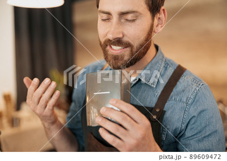 Smiling barista enjoys the aroma of coffee beans 89609472
