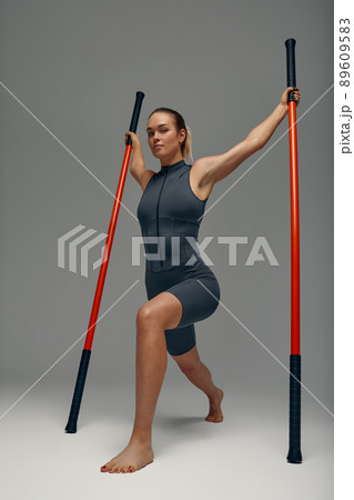 beautiful girl in sports uniform is training kung fu in the studio, fighter athlete, practicing martial arts with a stick 89609583
