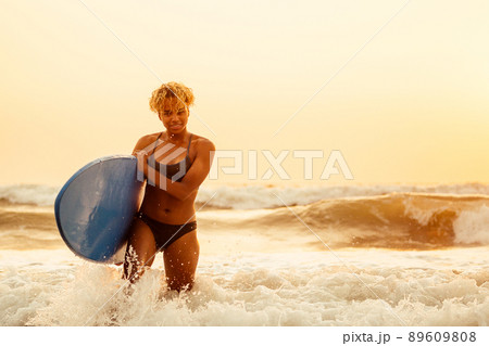 african american surfer girl in water enjoying sunset 89609808