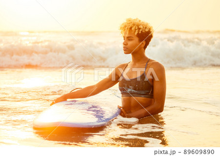 african american surfer girl in water enjoying sunset 89609890