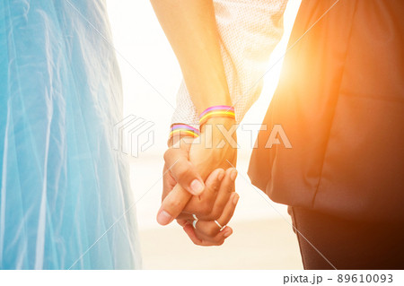 african american female groom in black suit and caucasian bride in dress in ceremony on tropical beach under wedding flover arch african american female groom in black suit and caucasian bride in dress in ceremony on tropical beach under wedding flover arch 89610093