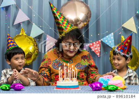 Celebrating elderly woman birthday, blowing candles on homemade baked cake 89610184