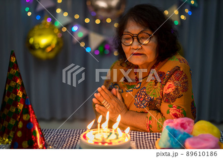 Celebrating elderly woman birthday, blowing candles on homemade baked cake Celebrating elderly woman birthday, blowing candles on homemade baked cake 89610186