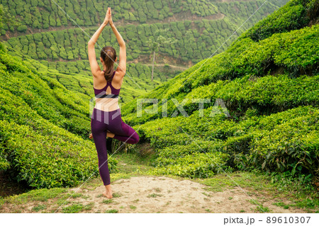 woman in violet cloth doing yoga on tea plantations in Munnar hill Kerala India woman in violet cloth doing yoga on tea plantations in Munnar hill Kerala India 89610307