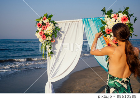 Decorator working with flowers composition for wedding arch on ocean beach 89610589