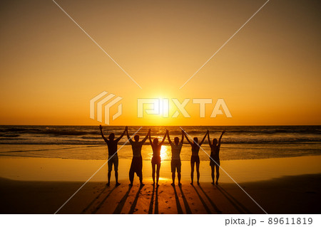 six health people in stand hatha position with hand up raced and breath full chest in Goa India beach at sunset 89611819